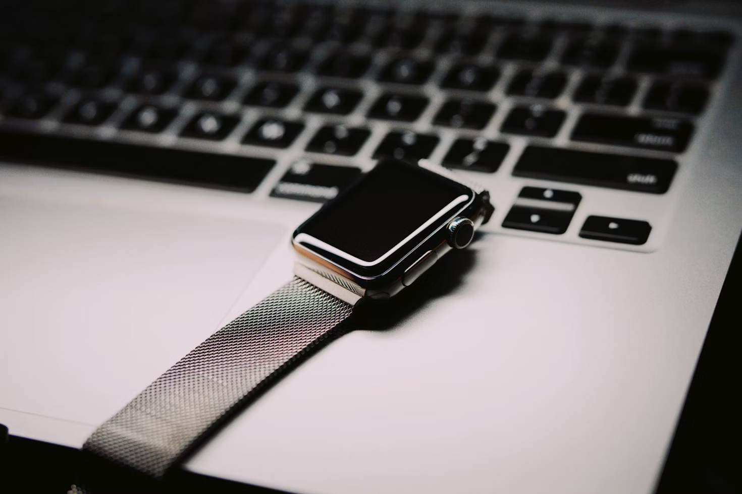 Como limpar pulseira Apple Watch: imagem de relógio com pulseira de metal sobre um notebook